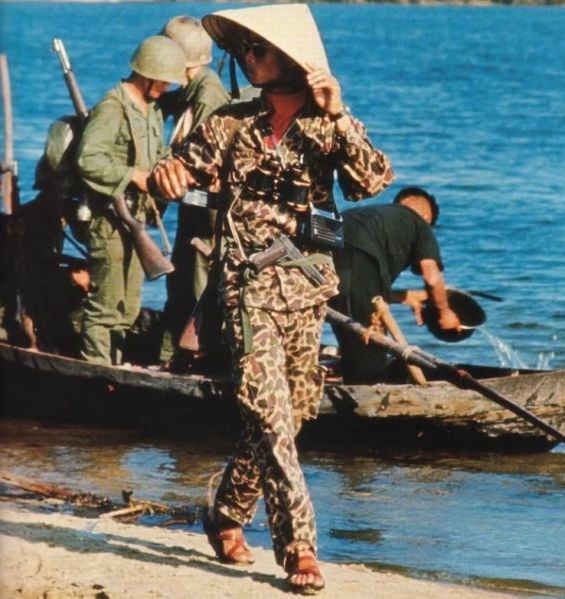 a ranger of the ARVN strikes a pose with sandals, sunglasses, civilian transistor radio, and nón lá hat. duck camo frog lizard and a M1911